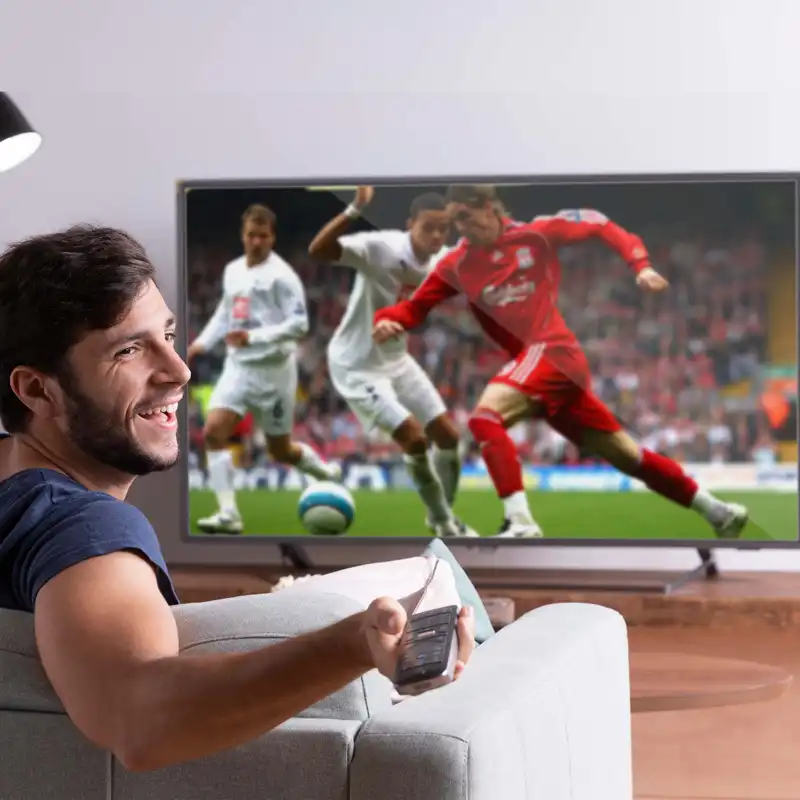 Spor yayını gösteren televizyonun önünde oturan kişi